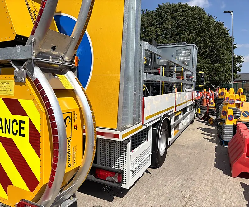 An impact protection vehicle in the yard beside rows of cones, signs and barriers