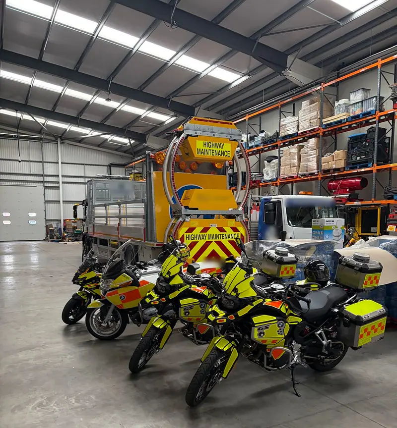 EST’s motorcycle unit lined up in our warehouse beside an impact protection vehicle and racked equipment