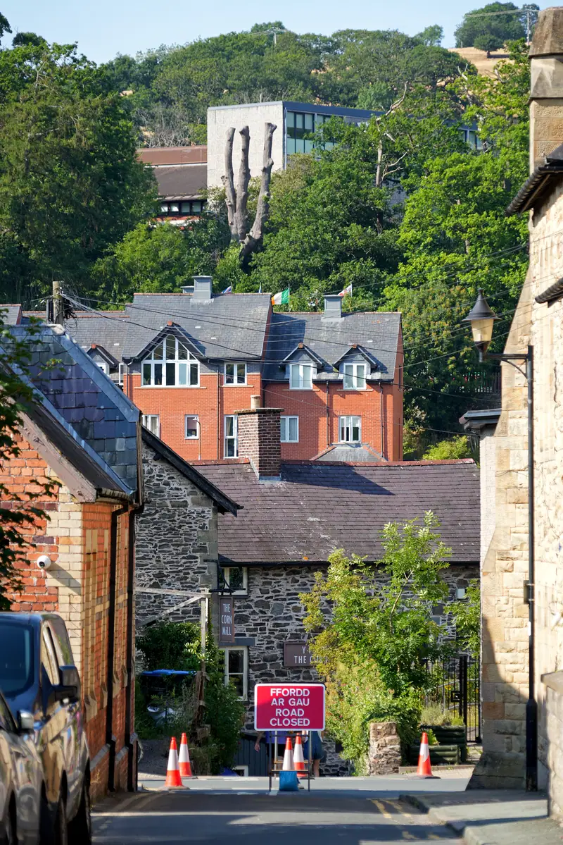 A bilingual Ffordd ar Gau, Road Closed sign and cones across a street in Llangollen