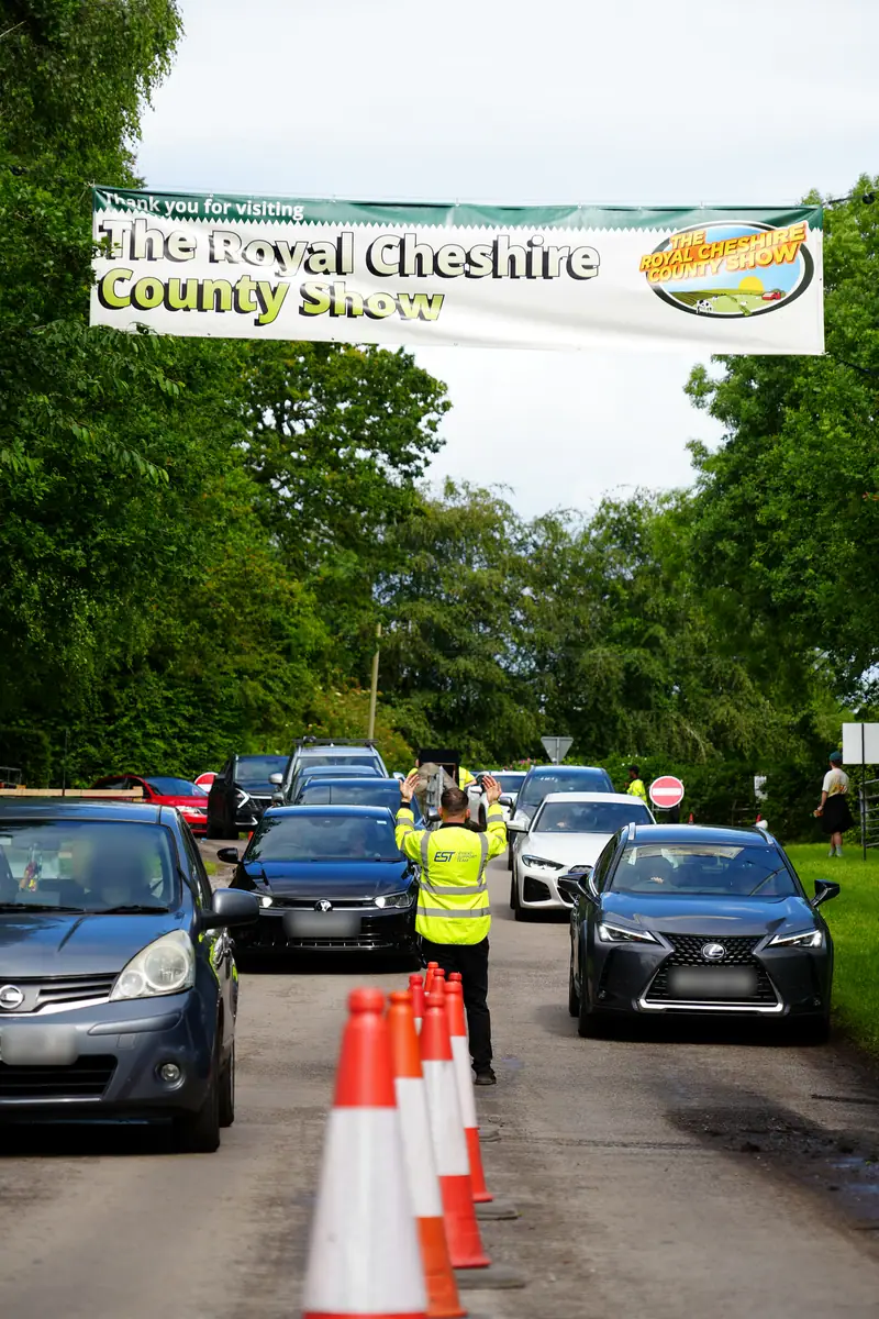An EST marshal directing cars out under the Royal Cheshire County Show banner