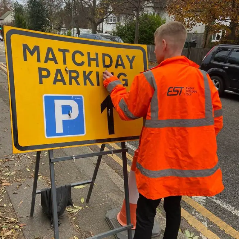 An EST operative fixing a matchday parking sign on a frame