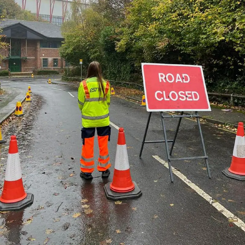An EST steward beside a Road Closed sign and cones