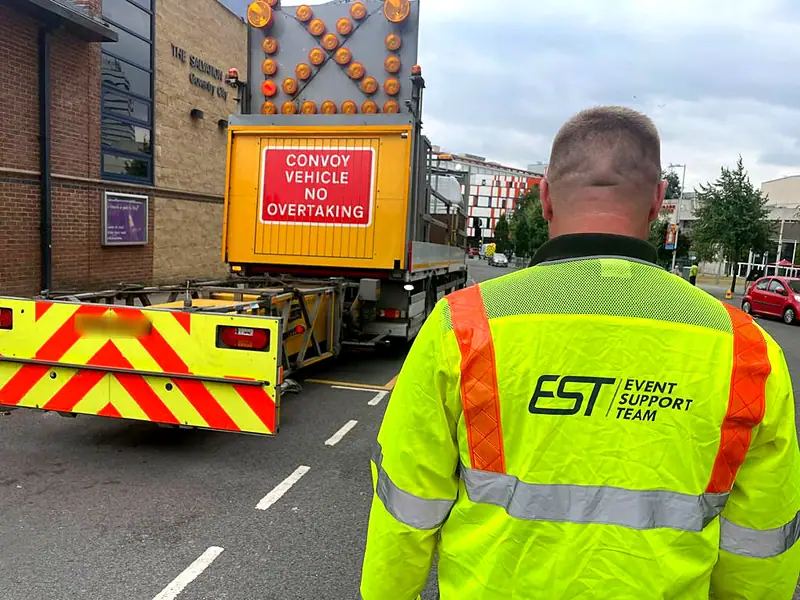 An EST operative beside an impact protection vehicle carrying a Convoy vehicle, no overtaking sign
